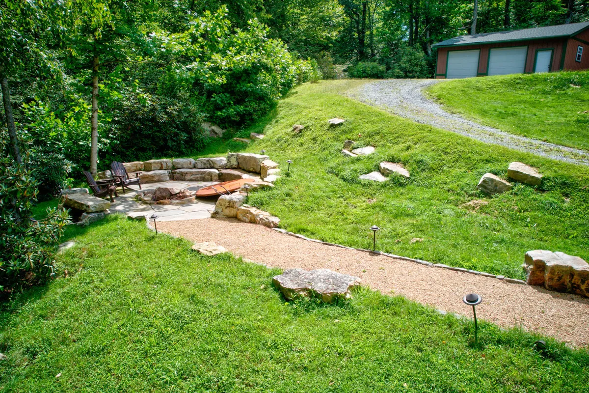 An inviting hot tub and adjacent stone seating area set amidst verdant surroundings. The scene captures a tranquil space for group relaxation, laughter, and stargazing—whether soaking in the hot tub or unwinding on the stone benches.