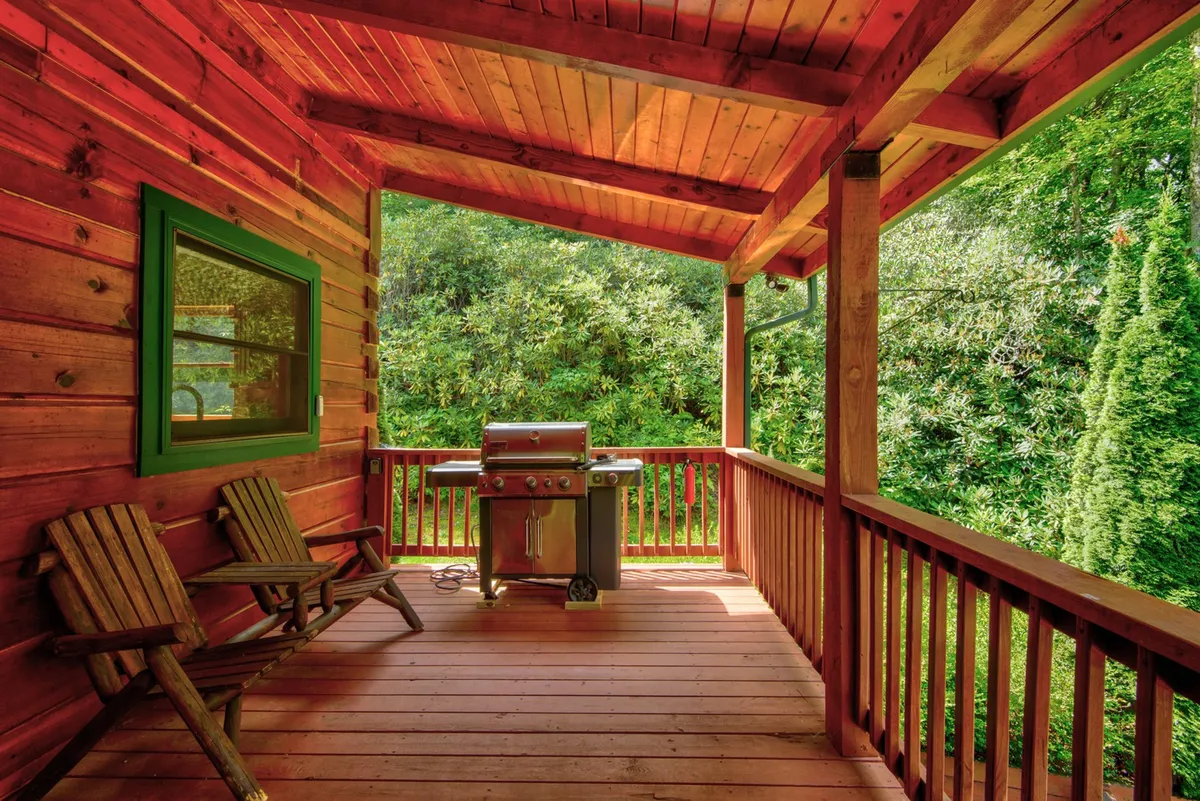 This exterior image features a grill and wooden chairs set in a lush green environment, suggesting opportunities for al fresco dining and relaxation. The setup hints at private outdoor moments, surrounded by tranquil nature.